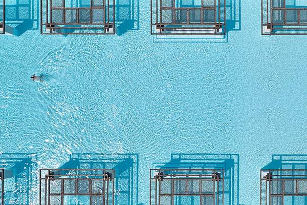 Obersicht des Amirandes Grecotel Boutique Resort Schwimmbads mit einer Person im Wasser.