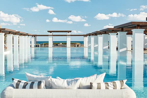 Infinity-Pool im Amirandes Grecotel Boutique Resort mit weißen Säulen und Sonnenliegen