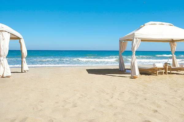 Zwei weiße Gazebos am Strand des Amirandes Grecotel Boutique Resorts mit Paar dahinter
