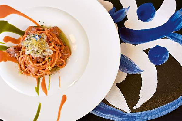 Ein Teller mit einem Gericht von Amirandes Grecotel Boutique Resort, bestehend aus Nudeln mit Fleisch, Tomatensoße und gewürzt.