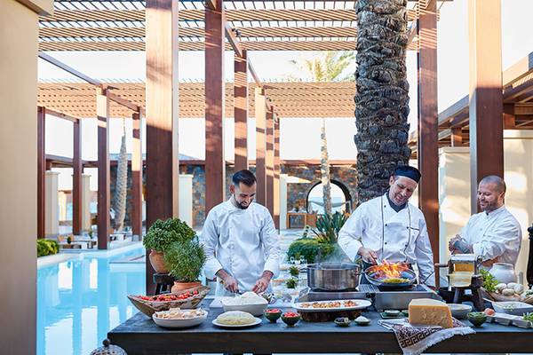 Drei Köche am Amirandes Grecotel Boutique Resort, die vor einem Swimmingpool kochen.