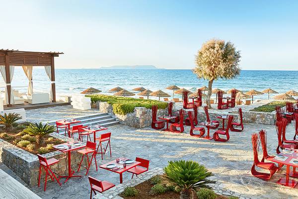 Außenterrasse des Amirandes Grecotel Boutique Resorts mit Blick auf das Meer und rote Möbel.