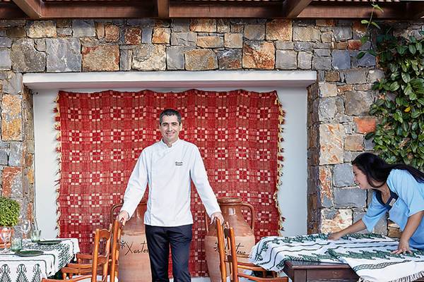 Ein Mitarbeiter des Amirandes Grecotel Boutique Resort steht lächelnd im Garten des Hotels.