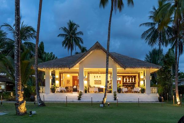 Außenansicht des Kantary Beach Hotel, Villas & Suites bei Nacht mit beleuchteten Wegen und Palmen.