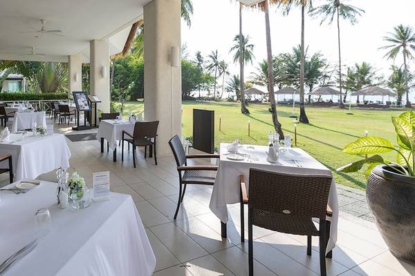 Außenbereich des Kantary Beach Hotel mit Tischen und Stühlen auf der Terrasse.
