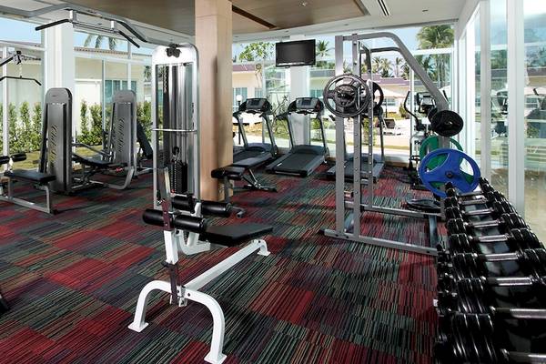 Fitness-Center im Kantary Beach Hotel mit verschiedenen Geräten und großen Fenstern.