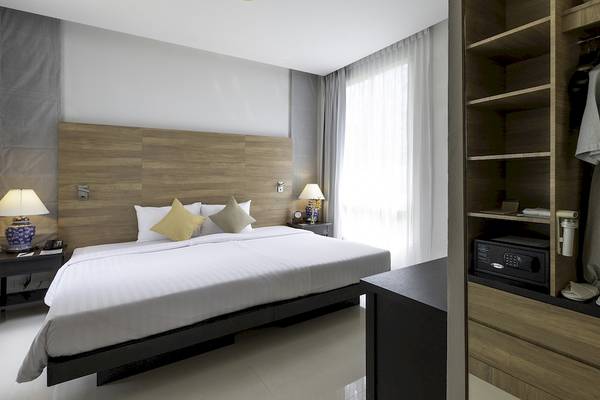 Schlafzimmer im Kantary Beach Hotel, Villas & Suites mit Doppelbett, Nachttischen, Lampen und Schrank.