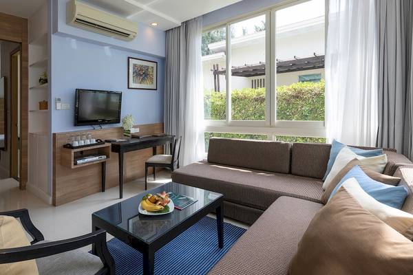 Innenansicht des Kantary Beach Hotel Zimmers mit Wohnzimmer, Schreibtisch, Fernseher und Schlafzimmer.