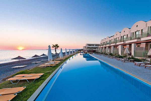 Ein Swimmingpool am Giannoulis Grand Bay Beach Resort mit Sonnenuntergang im Hintergrund.