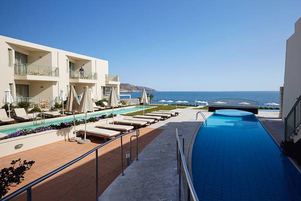 Außenbereich des Giannoulis Grand Bay Beach Resort mit Swimmingpool und Sonnenliegen