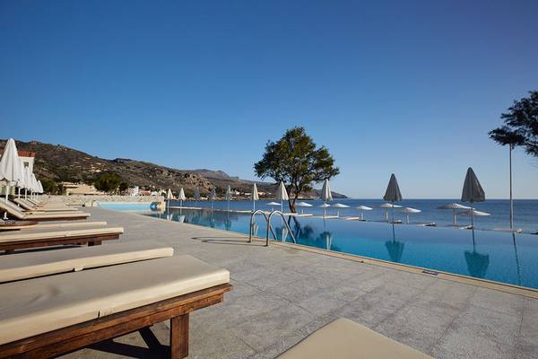 Außenpoolbereich des Giannoulis Grand Bay Beach Resorts mit Liegestühlen und Sonnenschirmen