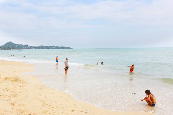 Menschen am Strand von Pavilion Samui Villas & Resort, einige schwimmen im Wasser