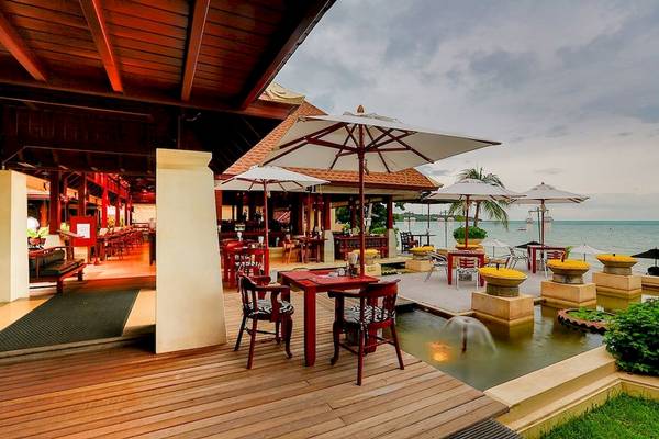 Außenbereich des Pavilion Samui Villas & Resort mit Tischen, Stühlen und Schirmen am Meer