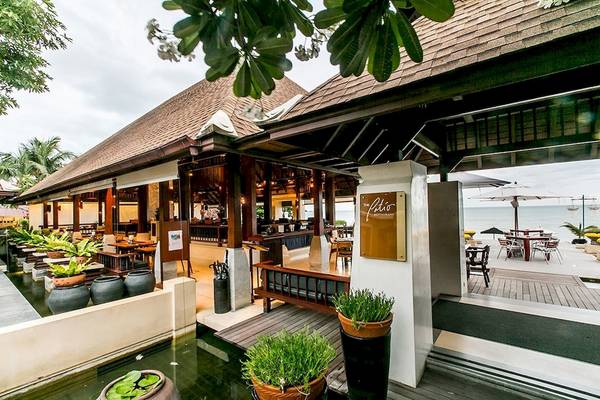 Außenbereich des Pavilion Samui Villas & Resort mit Tischen und Stühlen unter Schirmen.
