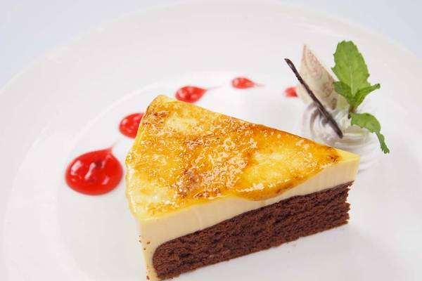 Schnitt eines Schokoladenkuchens mit Creme und Beeren auf einem weißen Teller