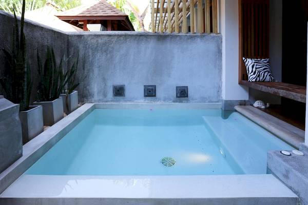 Außenpool des Pavilion Samui Villas & Resort mit Betonwänden und Pflanzen in Töpfen.