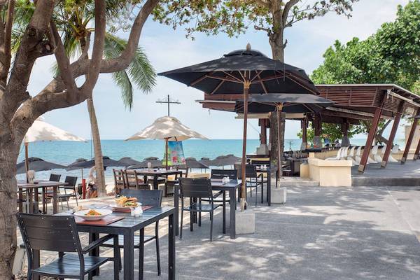 Strandrestaurant des Pavilion Samui Villas & Resort mit Tischen und Stühlen unter Sonnenschirmen.