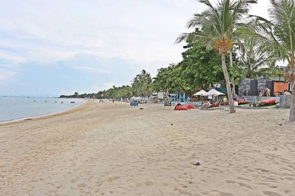 Strand des Pavilion Samui Villas & Resort mit Sonnenschirmen und Liegen am Wasser