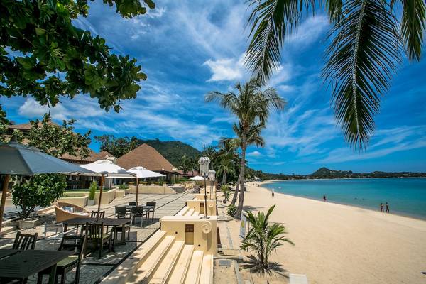 Außenbereich des Pavillon Samui Villas & Resort mit Strand, Palmen und Sonnenschirmen.