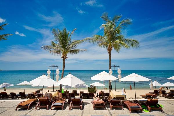 Strandszene im Pavilion Samui Villas & Resort mit Sonnenliegen, Sonnenschirmen und Palmen