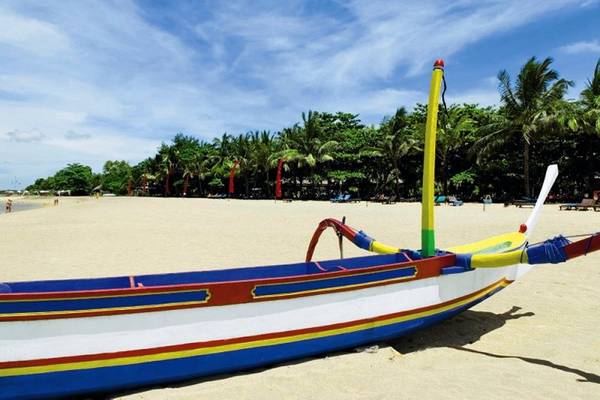 Farbiges Boot am Strand des Mercure Resort Sanur mit Bäumen und blauem Himmel