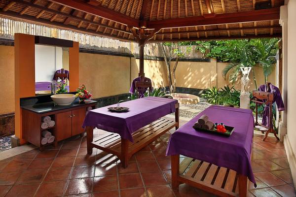 Massagebereich im Mercure Resort Sanur mit zwei Liegen und einem Waschbecken.