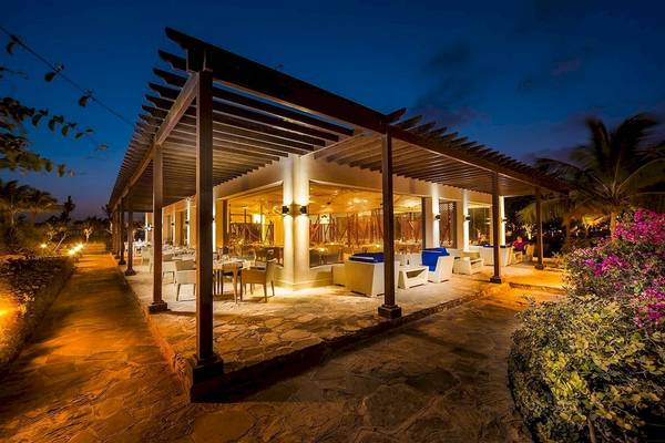 Außenbereich des Juweira Boutique Hotels bei Nacht mit beleuchteten Tischen und Stühlen.