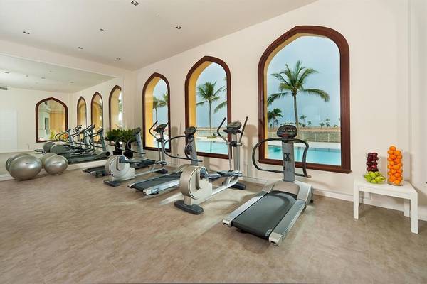 Fitnessraum im Juweira Boutique Hotel mit Blick auf den Pool und Palmen
