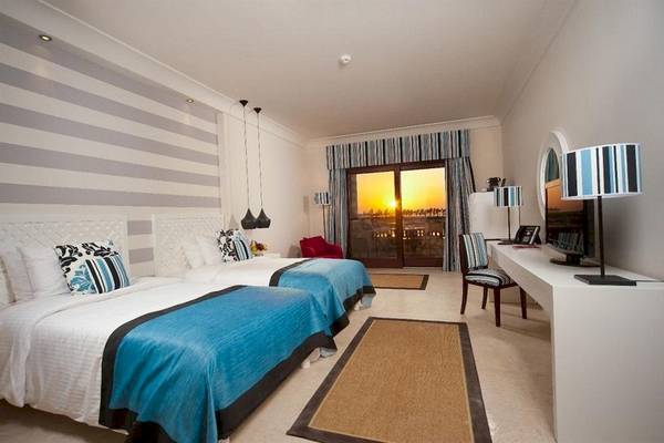 Doppelzimmer im Juweira Boutique Hotel mit zwei Betten und Blick auf den Sonnenuntergang.