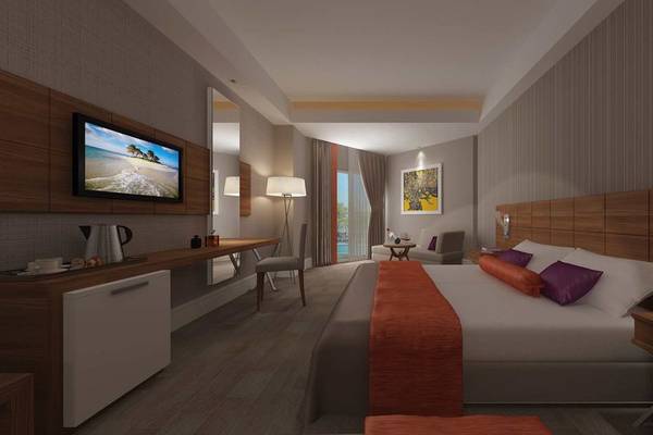 Schlafzimmer im Side Sunport Hotel & Spa mit Fernseher, Schreibtisch, Sessel und Aussicht auf das Meer.