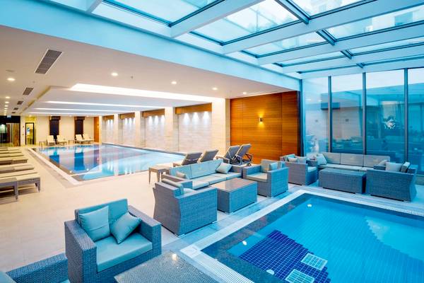 Innenpool des Side Sunport Hotel & Spa mit Loungebereich und Sonnenliegen.