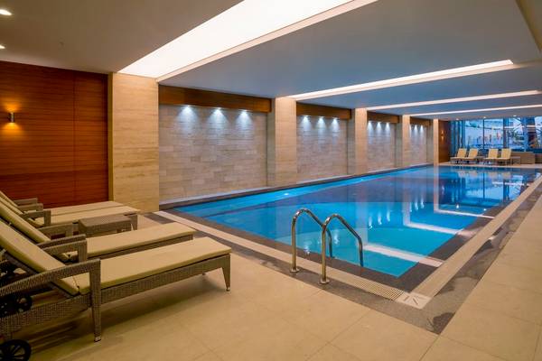 Innenpool des Side Sunport Hotel & Spa mit Lounge-Sesseln und blauem Wasser.