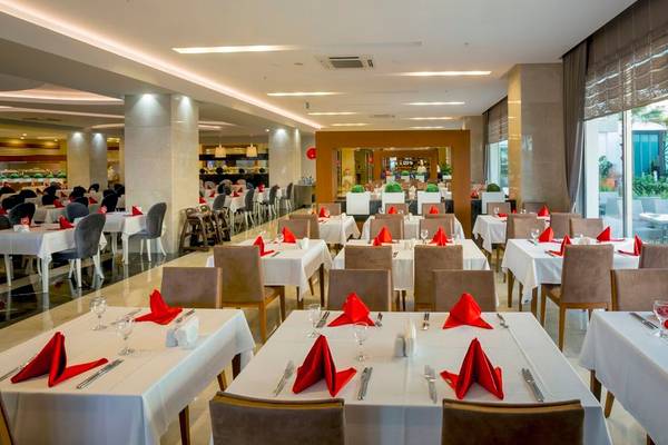 Restaurant im Side Sunport Hotel & Spa mit gedeckten Tischen und roten Servietten.