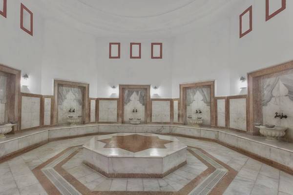 Innenbereich der Sauna im Kremlin Palace Hotel mit weißen Marmorwänden und acht Waschbecken.