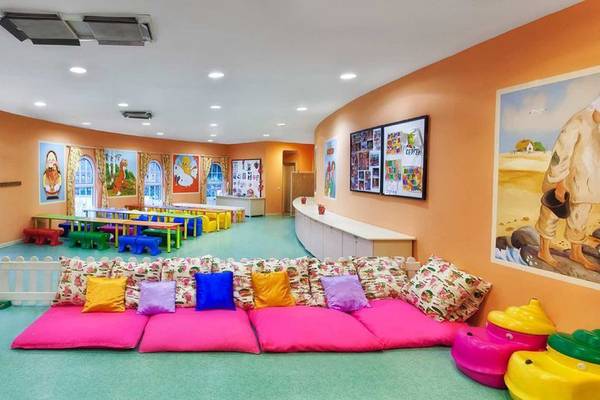 Kinderzimmer im Kremlin Palace Hotel mit bunten Möbeln, Kissen und Gemälden an der Wand.