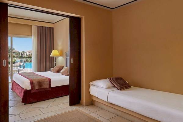 Zimmer im Jaz Mirabel Beach Hotel mit zwei Betten, Balkon und Poolblick.