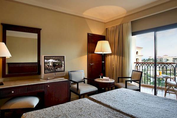 Doppelzimmer im Jaz Mirabel Beach Hotel mit zwei Betten, Schreibtisch, Fernseher und Balkon.
