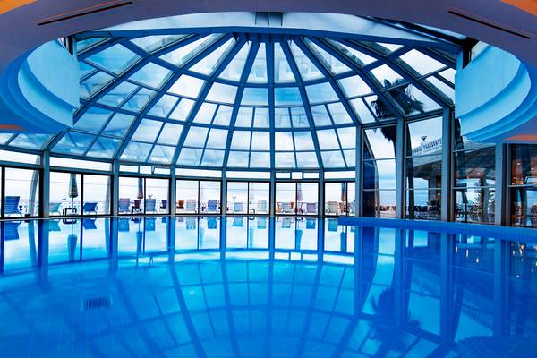 Innenpool des Sunrise Queen Luxury Hotel mit Glasdach und Blick auf den Ozean