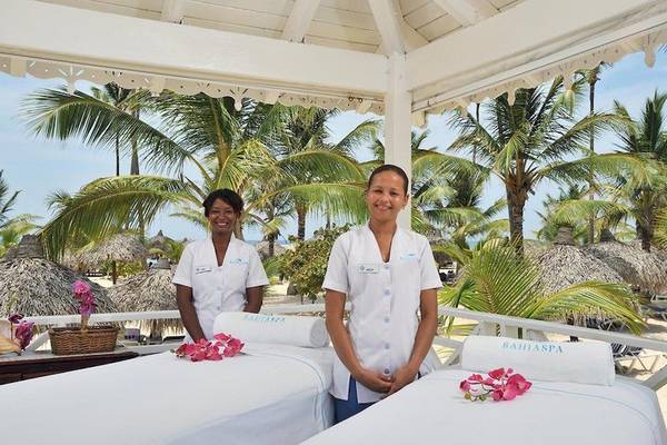Zwei Frauen im Spa-Bereich des Bahia Principe Luxury Esmeralda mit Massagebetten und Palmen im Hintergrund.