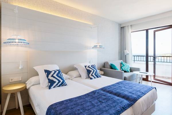 Hotelzimmer mit zwei Betten, Balkon und Aussicht auf das Meer.