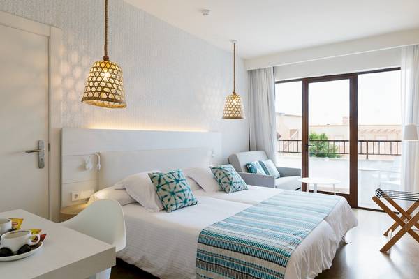 Doppelzimmer im Leonardo Royal Hotel Ibiza Santa Eulalia mit zwei Betten, Wohnzimmer und Balkon.