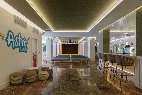 Astro Family Bereich im Leonardo Royal Hotel Ibiza Santa Eulalia mit Lounge-Sesseln und einer Bühne.