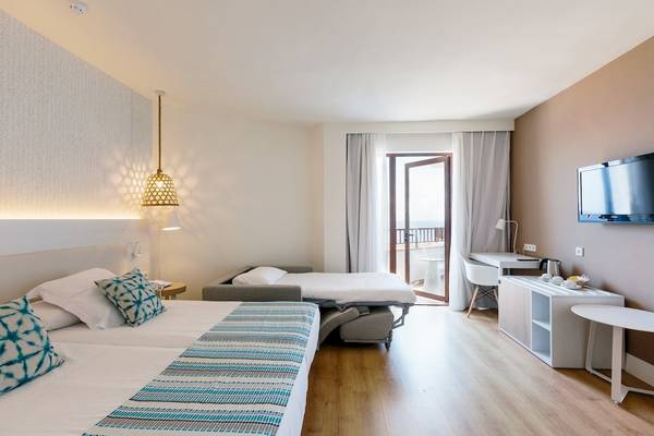 Doppelzimmer im Leonardo Royal Hotel Ibiza Santa Eulalia mit zwei Betten, einem Sofa und einer Terrasse.