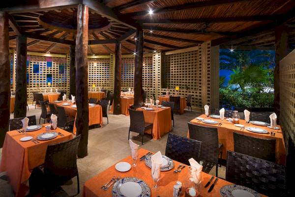 Innenbereich des Restaurants im Hard Rock Hotel Cancun mit orange Tischdecken und runden Tischen