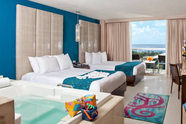 Suite im Hard Rock Hotel Cancun mit zwei Betten, Whirlpool und Meerblick.