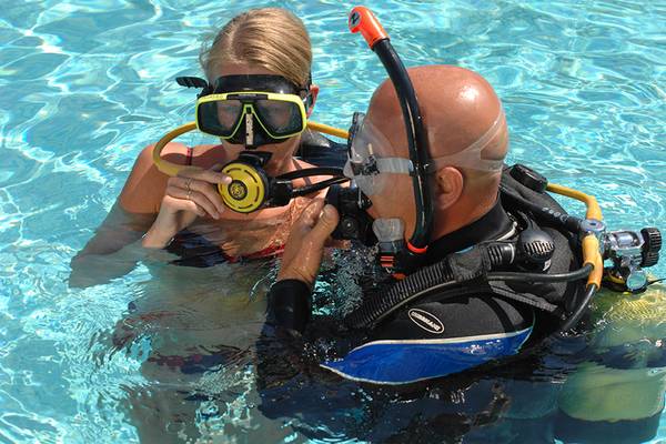 Eine Frau und ein Mann tauchen im Schwimmbecken des Marti Resorts, beide tragen Tauchausrüstung.