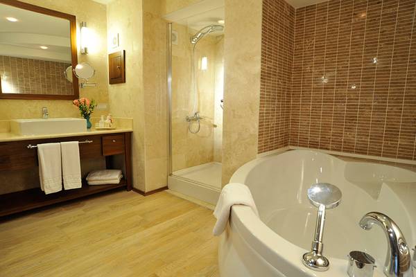 Badezimmer im Marti Resort mit Badewanne, Dusche, Waschbecken und Spiegel