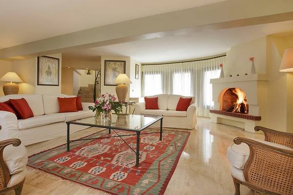 Wohnzimmer im Marti Resort mit weißen Sofas, rote Kissen, Kamin und Teppich.