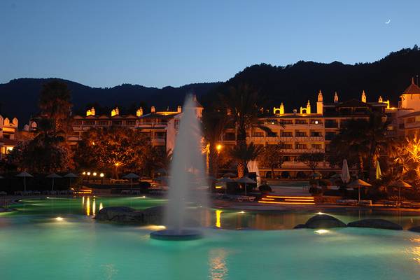 Abendlicher Blick auf das Marti Resort mit beleuchtetem Pool und Fontäne.