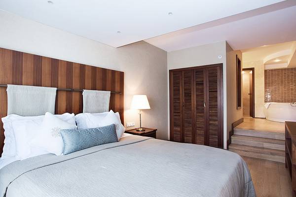 Schlafzimmer im Marti Resort mit einem großen Bett, weißen Kissen, einer Lampe und einem Badezimmer mit Badewanne.